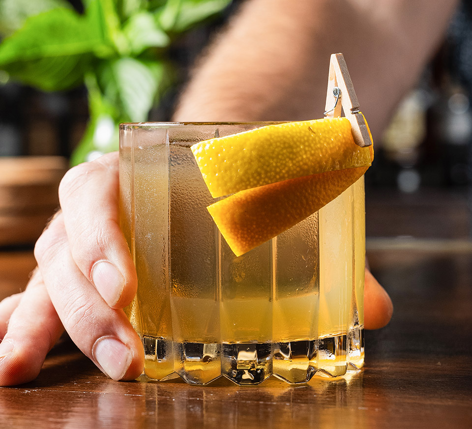 Bartender showing cocktail with orange slices around the rim at Bottled in Bond in Frisco, Texas